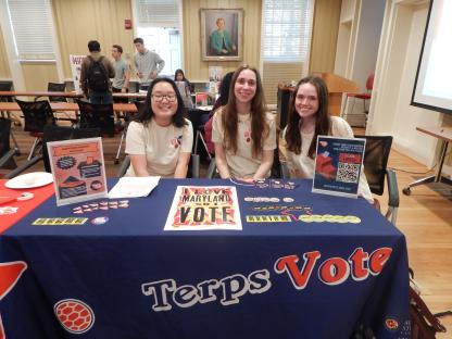 3 students behind table smiling