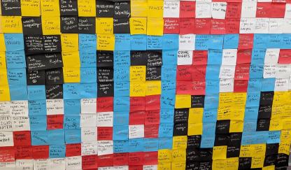 post it notes in red, white, black, yellow in background with VOTE spelled in blue post-its on top